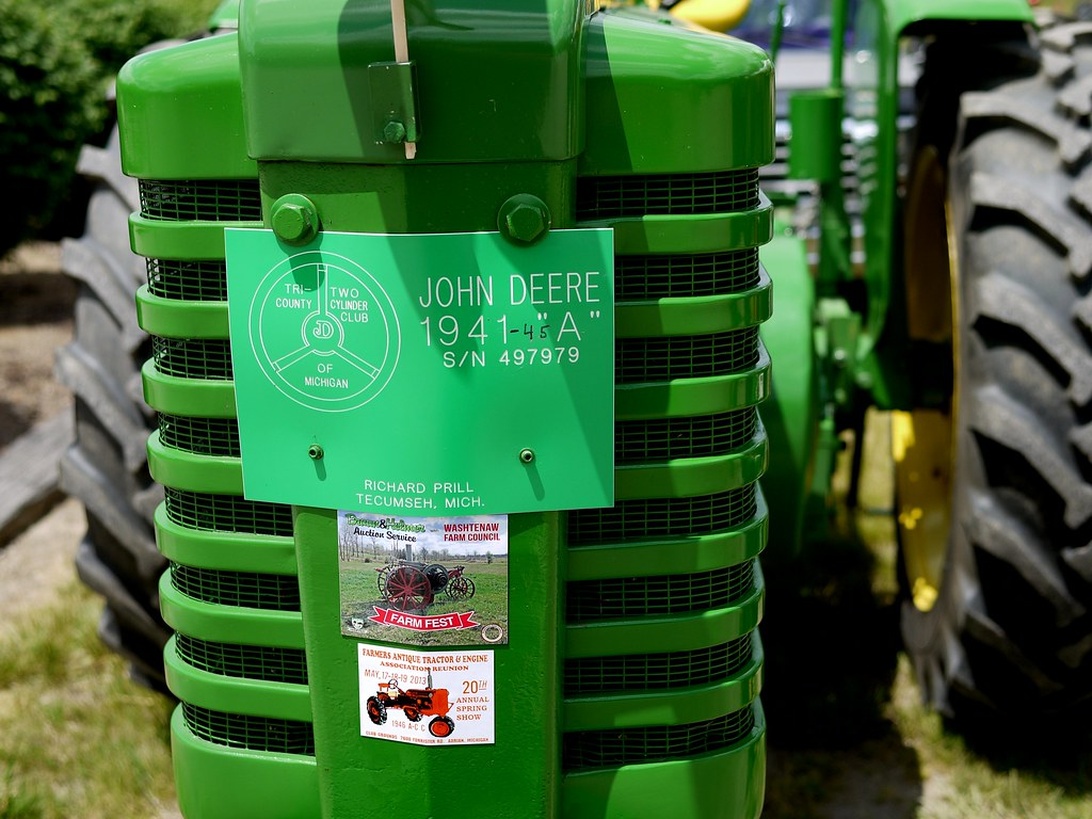 Närbild på en restaurerad grön John Deere-traktor från 1941 med auktionsdekaler.
